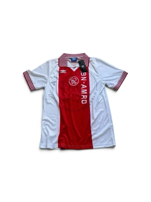 Ajax fotbollströja röd/vit med krage - Ajax Amsterdam matchtröja i klassisk röd och vit design med krage och ränder på ärmslut och krage. Framsidan har klubbmärke och sponsor, baksidan har Kluivert och nummer 9. Tillverkad i lätt och ventilerande material, perfekt för fotboll eller samling. Kom gärna med bud!