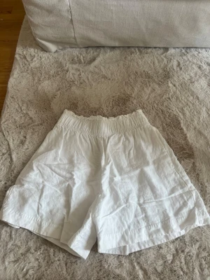 Linne shorts  - Säljer ett par fina vita linne shorts med bred resår i midjan. Knappt använda i storlek xs från H&M