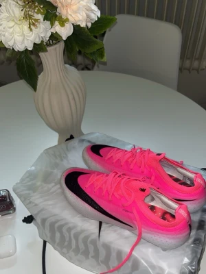 Nike Mercurial Vapor rosa fotbollsskor - Säljer ett par Nike Mercurial Vapor fotbollsskor i en riktigt snygg rosa färg med svarta detaljer och vit sula. Skorna har snörning och är designade för gräsplan. Perfekta för dig som vill sticka ut på planen och få bra grepp och känsla med bollen.