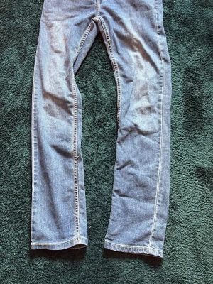 Levi's 511 Slim ljusblå jeans - Säljer ett par Levi's 511 Slim jeans i ljusblå denim. Jeansen har klassisk femficksdesign, dragkedjegylf och raka ben. Perfekta för dig som gillar en smalare passform och tidlös stil. Levi's-logga på knappen och etikett i midjan.