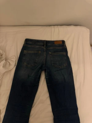Blå jeans från ONLY - Säljer ett par klassiska blå jeans från ONLY med raka ben och två bakfickor. Jeansen har en snygg tvättad look och detaljerade sömmar. Perfekta till vardags och lätta att matcha med olika stilar. Nästan helt nya 