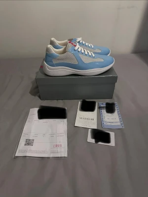 Blå och vita sneakers med meshdetaljer - Snygga sneakers i ljusblått med vita detaljer och meshpaneler för extra ventilation. Skorna har vita snören, tjock vit sula och en röd detalj på hälen. Perfekta för dig som vill ha en fräsch och sportig look till vardags.