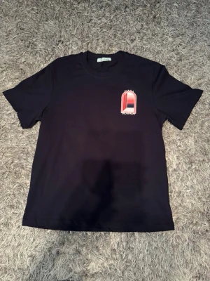 Svart Casa Blanca t-shirt med tryck - Snygg svart t-shirt från Casa Blanca med stort grafiskt tryck i rött, rosa och vitt på ryggen och mindre tryck på bröstet. Klassisk passform och rund halsringning. Perfekt för dig som gillar streetwear och vill sticka ut.
