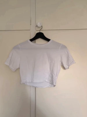 Vit croppad t-shirt - Säljer en enkel och stilren vit croppad t-shirt med rund hals och korta ärmar. 