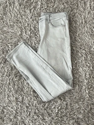 Ljusgrå slimjeans - Snygga ljusgrå jeans med rak passform och klassisk femficksdesign. Jeansen har normal midja och är tillverkade i ett mjukt denimtyg som ger en avslappnad look. Perfekta för dig som gillar stilrena och ljusa basplagg.