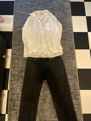 Vit linneskjorta med knappar - Klassisk vit skjorta i linne med lång ärm och knäppning framtill. Skjortan har en bröstficka och avslappnad passform, perfekt för en stilren look. Snygg att bära både öppen och stängd.