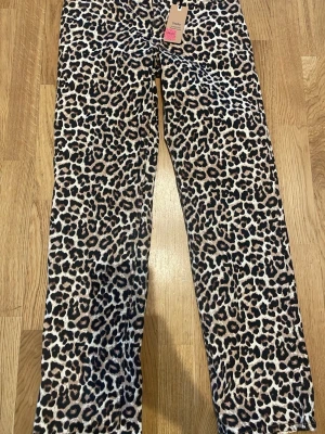 Leopardmönstrade raka jeans - Snygga raka jeans med leopardmönster i beige, brunt och svart. Jeansen har hög midja och klassisk femficksmodell. Perfekta för dig som vill sticka ut och addera lite edge till din outfit.