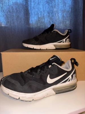 Nike buty  - Svarta Nike Air Max sneakers med vit sula och vit swoosh-logga på sidan. Skorna har mesh- och syntetmaterial i ovandelen, synlig Air Max-dämpning i hälen och svarta skosnören. Snygg kontrast mellan svart och vitt samt diskreta detaljer på hälen. Punkterad pump vilket är anledning till priset.