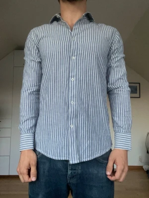 Randig linneskjorta  - Blå/vit randig linneskjorta från Bruun & Stengade. Tillverkad i 70% bomull och 30% linne. Strl S. Inga defekter. Modellen är 178 cm och väger 77 kg. Hör gärna av dig vid frågor!