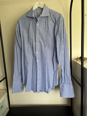 Blåvit randig skjorta - Klassisk blå och vit randig skjorta. Tillverkad i bomull för en skön känsla och snygg passform. Perfekt för dig som gillar en tidlös och fräsch look. Ny pris 1000