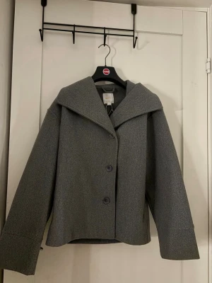Grå ullrock med bred krage - En jätte fin kappa i grå är i storlek 158/164 men skulle säga att den är ganska stor i storlek så den skulle även passa för någon som har 170.