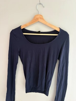 Mörkblå långärmad topp - En enkel och stilren mörkblå långärmad topp med rund halsringning. Toppen har en tight passform och är tillverkad i mjukt bomullsmaterial, perfekt att matcha med jeans eller kjol. Använd fåtal gånger. Skriv privat för mer information. 