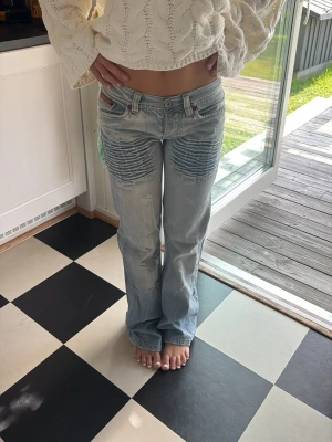 Ljusblå bootcut jeans med detaljer - Intressekoll på ett par ljusblå bootcut jeans från replay med coola ribbade detaljer på låren och klassiska fem fickor. Jeansen har låg midja och en avslappnad passform. Materialet är denim i bomull. Perfekta för en trendig och avslappnad stil.