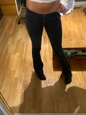 Svarta low rise bootcut jeans💘 - Säljer ett par svarta bootcut jeans med låg midja och klassisk femficksdesign. Jeansen har en tight passform upptill och släpper ut lite ner till