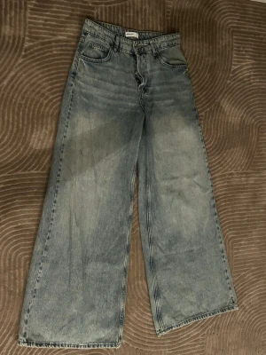 Gråblå wide leg jeans - Säljer ett par gråblå jeans med breda ben och hög midja. Jeansen har klassisk femficksdesign och är tillverkade i denim. Perfekta för dig som gillar en avslappnad och trendig stil.