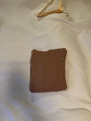 Brun/beige hoodie lylescott  - Säljer en brun hoodie med huva. Hoodien har ribbade muddar vid ärmslut och nederkant. Perfekt för dig som gillar en enkel men snygg stil.