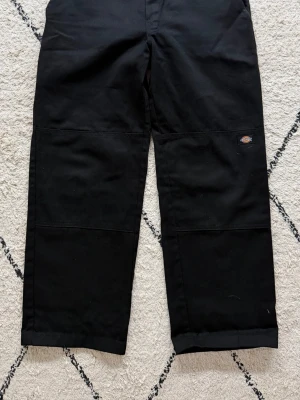 Nya workpants från Dickies W32/L30 - Helt nya svarta workpants  från Dickies med raka ben och avslappnad passform. Byxorna har klassisk Dickies-logga på sidan, förstärkta sömmar över knäna och bakfickor. Materialet är slitstarkt, storlek W32/L30. Köpte för små till mig. Bra pris då nypris är ca 750kr.
