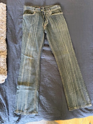 Vintage- Blå Tomx jeans med vit slitning - Säljer ett par blå jeans från Tomx med tydliga vita slitningar och raka ben. Jeansen har knappgylf, fem fickor och coola detaljer med röda sömmar vid fickorna. Materialet är klassisk denim som ger en avslappnad och trendig look. Storlek W31 L32. Som nämnt är detta par vintage. Vid funderingar eller liknande är det bara att höra av sig! 