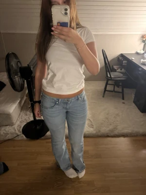 Ljusblå bootcut jeans - Säljer ett par ljusblå bootcut jeans med klassisk femficksdesign och låg midja. Jeansen har en lätt tvättad look och bootcut modell. Perfekta för en avslappnad och trendig stil.