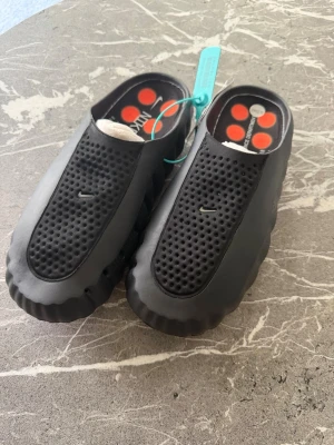 Svarta Nike tofflor med perforerad ovandel - Tja! Säljer dessa NIKE MIND tofflorna, helt oanvända då de var för små (endast prövade) i storlek 45/11uk. Låda tillkommer!!!! Tveka inte att skriva vid minsta fundering  . Pris kan ändras vid SNABB affär.