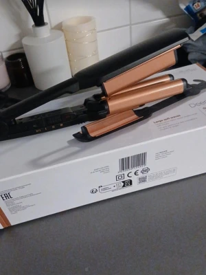 Vågtång med kopparfärgade plattor - Säljer en vågtång för hårstyling med snygga kopparfärgade plattor och svart handtag. Perfekt för att skapa stora, mjuka vågor i håret. Enkel att använda med flera värmeinställningar. Passar dig som vill fixa frisyren snabbt och smidigt.