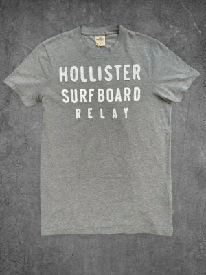 Vintage Hollister T-Shirt - Grå  - Vintage Hollister T-Shirt - Grå  Storlek: S Skick: Mycket bra Hör gärna av dig om du har några frågor, vill ha mått eller fler bilder! Finns en liknande T-shirt på profilen. Paketpris vid köp av båda!