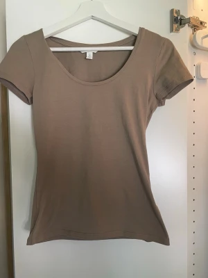 Beige basic t-shirt med rund hals - En enkel och stilren beige t-shirt med rund halsringning och korta ärmar. T-shirten har en normal passform och är tillverkad i mjuk bomull.