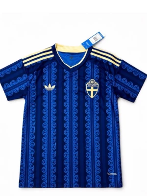Blå Sverige fotbollströja Adidas - Snygg blå fotbollströja från Adidas med Sveriges landslagsemblem på bröstet och gula detaljer. Tröjan har korta ärmar, V-ringning och ett unikt mönster i olika blå nyanser. Tre gula ränder på axlarna och Climacool-material för bra ventilation.