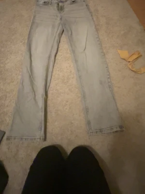 Ljusgråa raka jeans - Säljer ett par ljusblå jeans med rak passform och klassisk femficksdesign. Jeansen har normal midja och är tillverkade i denim. Perfekta för en avslappnad och trendig look.