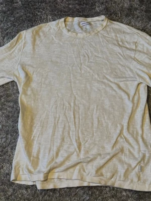 Beige t-shirt i bomull - En enkel beige t-shirt med rund hals och korta ärmar. Tillverkad i mjukt bomullsmaterial som känns skönt mot huden. Perfekt för en avslappnad och stilren look.