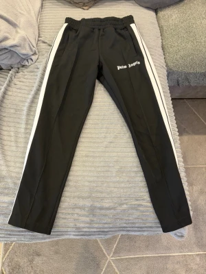 Palm angels - Säljer mina svarta Palm Angels byxor i storlek L. Passar även bra för dig som vanligtvis har storlek M. Byxorna är i nyskick och har en stilren design.