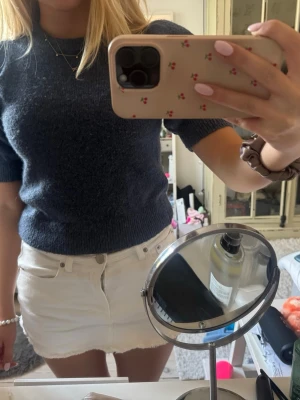 Mörkblå stickad puffärmströja - Säljer en mörkblå stickad tröja med korta puffärmar och ribbade muddar. Tröjan har en mjuk och lite tjockare kvalitet som ger en snygg siluett. Perfekt att matcha med kjol eller jeans för en trendig look.