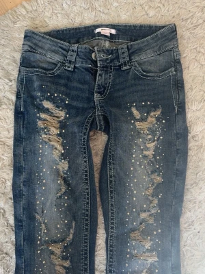 Mörkblå jeans med nitar - Snygga och unika jeans med slitningar och nitar / stenar. Storlek S, skriv i dm om mått eller frågor. Aldrig använda!!