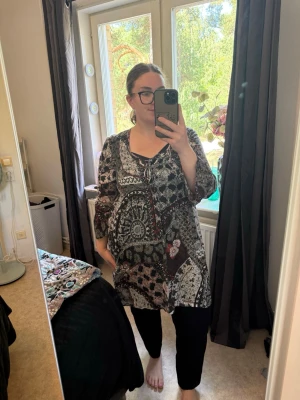 Mönstrad blus med v-ringning - Säljer en loose fit tunika/ klänning med svart, vit och grå patchwork-mönster. Blusen har v-ringning med snörning och trekvartsärm. Materialet känns som tunn polyester, perfekt för vår och sommar. Snygg och bekväm att styla till olika outfits. Från märket Odd Molly i storlek 4 som enligt deras storlekguide motsvarar en storlek XL. Mycket fint skick, jag hitta inga synliga anmärkningar eller defekter. 