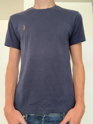 Ralph Lauren t shirt  - Ralph Lauren T-shirt i färgen mörkblå. Den är i storlek XS och i skicket 8/10. Modellen på bilden är 181cm och väger runt 60kg. Hör av dig om du har några funderingar 🙌