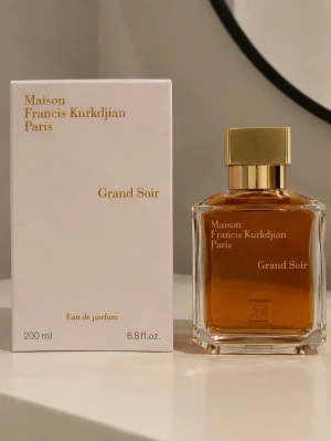 Grand Soir parfym Maison Francis Kurkdjian - Lyxig parfym Grand Soir från Maison Francis Kurkdjian Paris. Flaskan är elegant och fyrkantig i genomskinligt glas med guldlock och bärnstensfärgad vätska. Förpackningen är vit med guldfärgad text. Innehåller 200 ml Eau de Parfum.