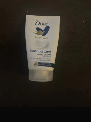 Dove Essential Care handkräm 75ml - Dove Essential Care handkräm för torr hud med ceramide restoring serum. Vit tub med blå och guld detaljer, smidig att ta med i väskan. Ger långvarig återfuktning och mjuka händer. Innehåller 75 ml. Lite använd!