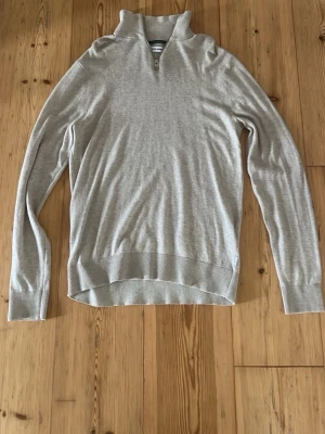 Beige stickad tröja Jack & Jones - Snygg beige stickad tröja från Jack & Jones med halv dragkedja vid halsen. Tröjan har lång ärm och ribbade muddar. Perfekt för lager på lager och enkel att matcha med olika outfits.