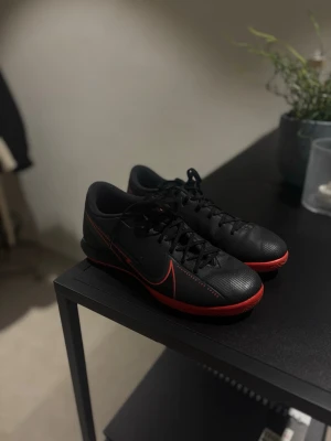Svarta Nike fotbollsskor med röd sula - Säljer ett par svarta Nike fotbollsskor med röd yttersula och röda detaljer. Skulle säga att det passar även 37,5-38,5. ( använda två gånger ) 