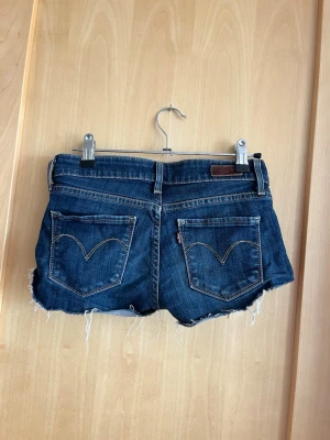 Mörkblå jeansshorts - säljer dessa super snygga lågmidjade jeansshorts från levis, storlek 24 i midjan men skulle säga att de passar som 23 med.
