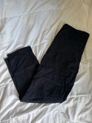 Svarta linnebyxor från Denim Day - Snygga svarta linnebyxor från Denim Day i storlek L. Byxorna har raka ben, hällor för skärp och stängs med knapp och dragkedja. Perfekta för en chill och stilren look under varmare dagar.