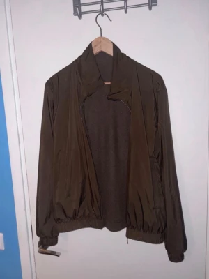 Loro Piana reversible  - Snygg brun vindjacka från Loro Piana, tillverkad i Italien. Jackan har dragkedja, elastiska muddar och är gjord i polyester med insida av kashmir. Perfekt för dig som vill ha en stilren och exklusiv look. Nypris runt 22k, finns en del hål därav priset. Tar eventuellt emot byten