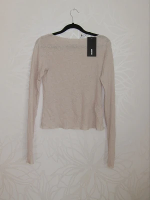 Beige långärmad topp - En enkel och stilren beige långärmad topp med rund hals, perfekt att matcha med jeans eller kjol.