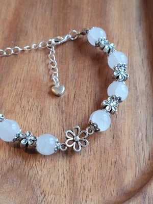 Summer Fling 🤍 Armband - Snyggt armband med vita runda glaspärlor i 8 mm och detaljer i silverfärgade blommor. Armbandet har en justerbar kedja med ett litet hjärta i slutet. Perfekt accessoar för att lyfta din stil med en söt och trendig touch.