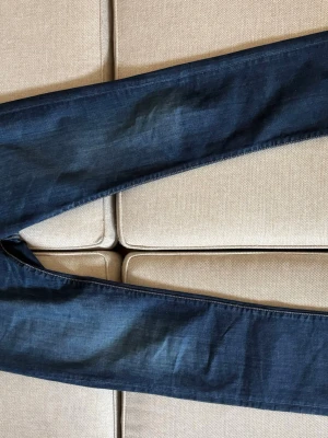Mörkblå raka jeans från Tramarossa - Säljer ett par mörkblå jeans med raka ben och snygga kontrastsömmar. Jeansen har knappgylf och detaljer i rött och vitt på insidan. Klassisk femficksmodell i slitstark denim, perfekta till vardagslooken.