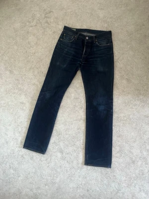 Levis 501 W30 L32 - Säljer ett par mörkblå jeans från Levis av modellen 501. Jeansen är mycket slitna med bland annat mindre hål i grenen men går säkert att laga för den händiga. Storleken är W 30 och L 32