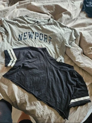Toppar H&M Divided XS/S - 2-pack toppar från H&M Divided XS/S  Två snygga toppar: en grå croppad t-shirt med Newport 1981-tryck (XS), en svart croppad t-shirt med vita ränder på ärmarna (S)  Perfekt för dig som gillar att mixa stilar och färger.  Kan även hämtas I Partille  E1