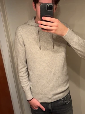 Kashmir hoodie - Mjuk och enkel grå hoodie med huva och snörning. Tröjan har långa ärmar och ribbade muddar vid ärmslut och nederkant. Perfekt för chill dagar och passar till allt. Materialet känns skönt mot huden och har en klassisk loose passform. Storlek S passar även xs.