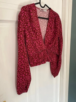Mönstrad rosa topp - Superfin mönstrad topp/blus från NA-KD.                           Toppen har lite vaddering i axlarna vilket ger ett fint lyft.                                                                                Endast använd en gång så är i nyskick!                                 Storlek 34✨