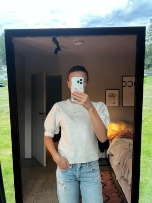 Beige stickad topp med puffärm - Säljer en beige stickad topp med puffiga korta ärmar och rund hals. Toppen har en ribbad kant nedtill och vid ärmsluten, vilket ger en snygg och modern look. Perfekt att matcha med jeans eller kjol för en trendig outfit. Aldrig använd, som nya!! Skriv för frågor🩷🫶🏼